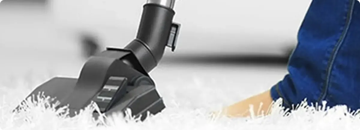 Close-up of a professional vacuuming a white carpet in Elm Grove.